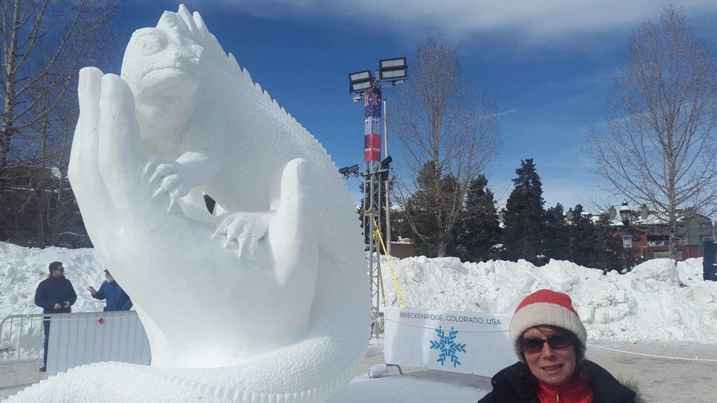 Snow sculpture of hand holding an iguana