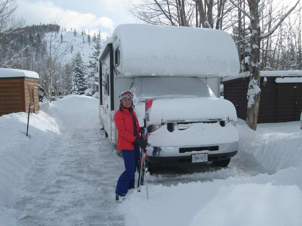 Standing outside the RV with skis