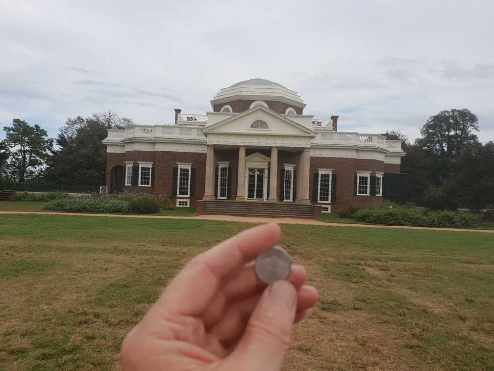 holding a nickle with a picture of Montello engraved on it with the house in the background