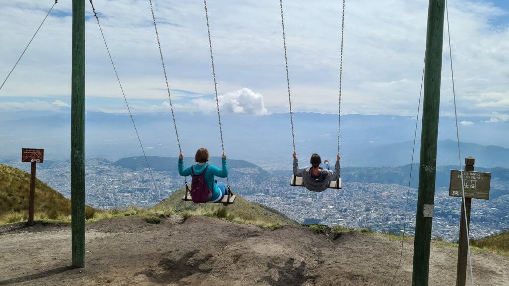 Two people on swings at top of the cable car in Quito