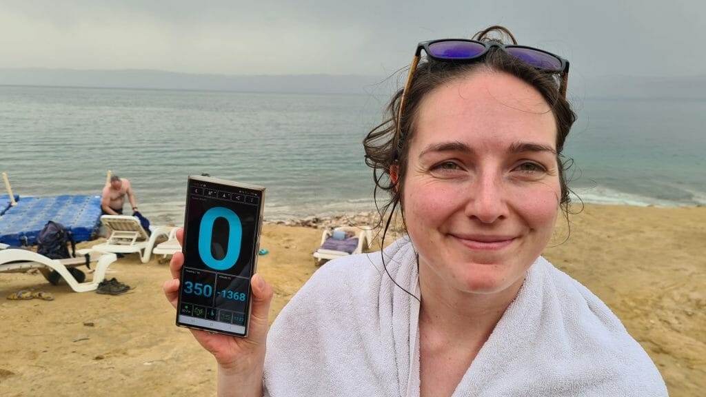 Girl holding mobile phone showing altitude below sea level at Dead Sea