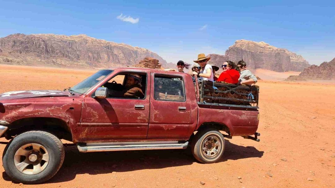 Battered looking Toyota pick up with people in back on a visit to Wadi Rum