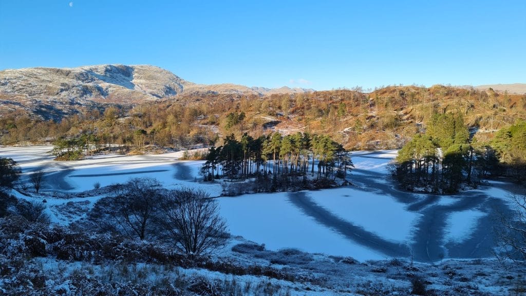 View over snow covered lake to fells behind